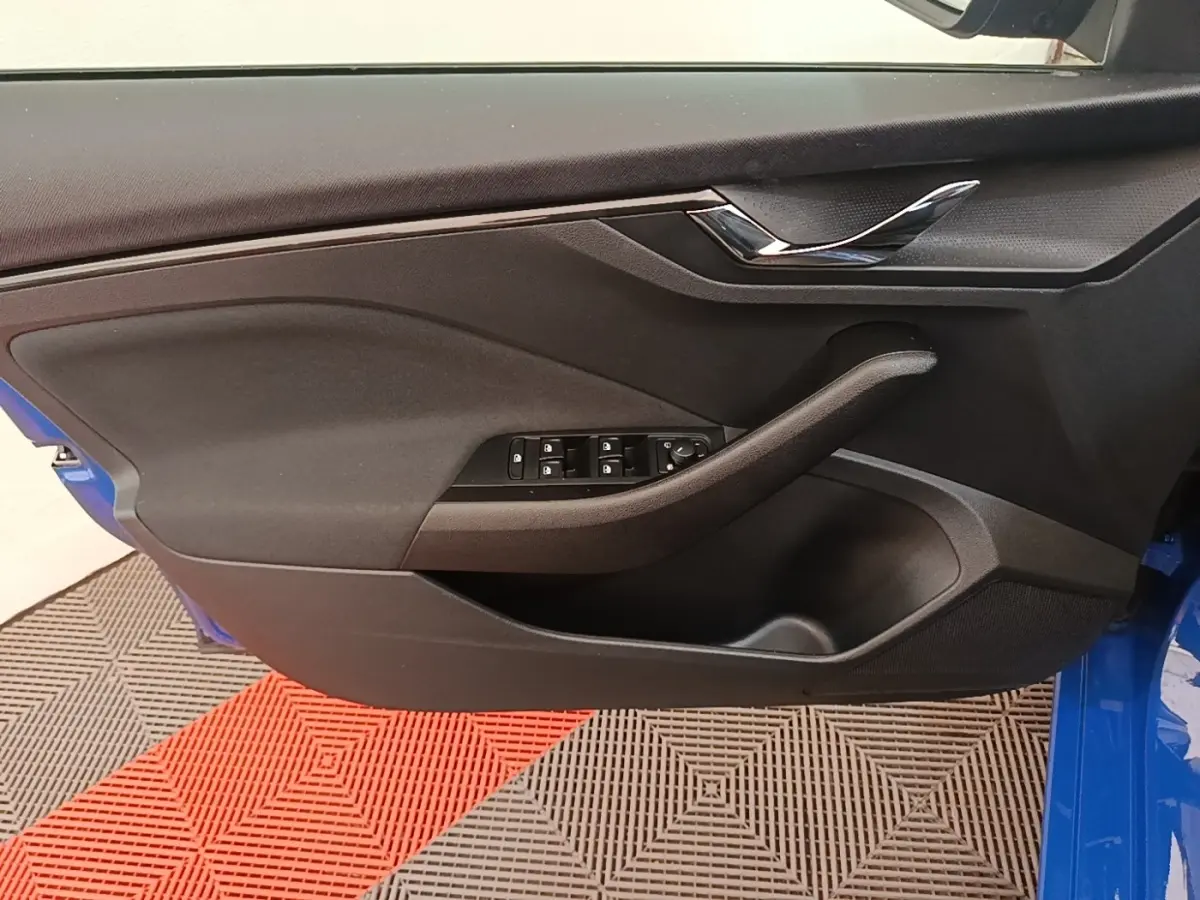 Vue rapprochée de la porte avant gauche d'une Skoda Scala bleue, avec commandes de vitres et poignée noire.
