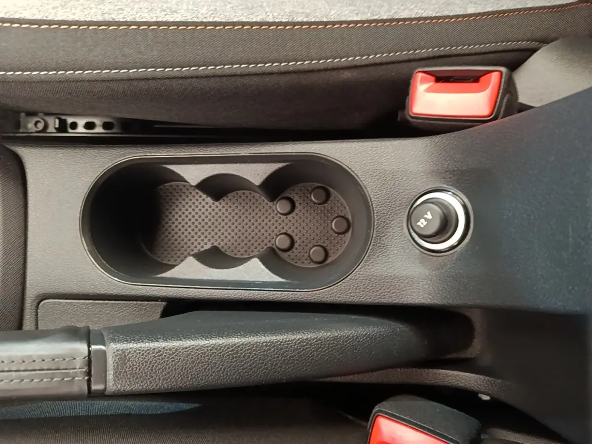 Vue rapprochée de la console centrale de la Skoda Scala 2024, montrant porte-gobelets, frein à main et prise 12V.