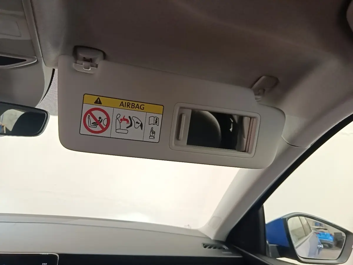 Détail du pare-soleil côté conducteur avec miroir intégré et avertissement airbag dans un Skoda Scala bleu 2024.