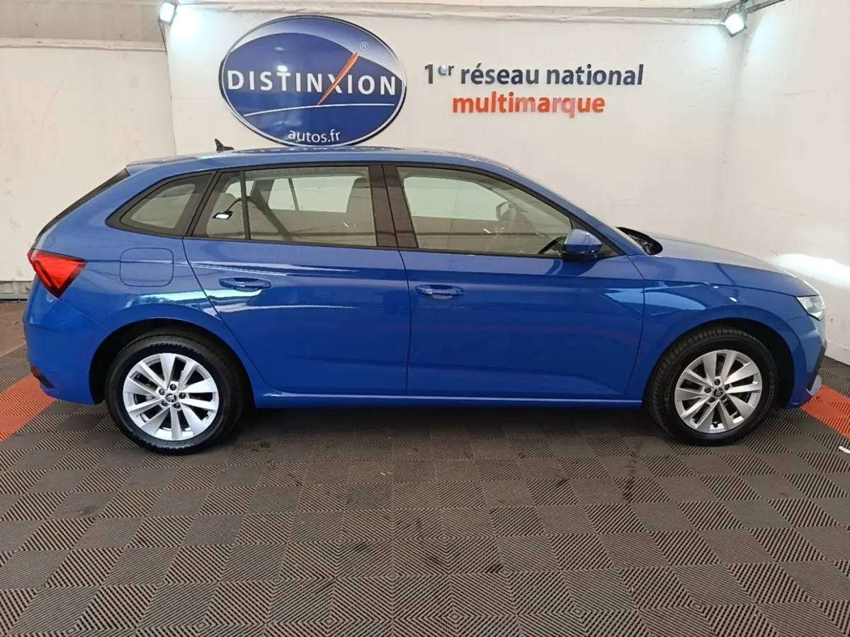 Profil droit d'une Skoda Scala bleu 2024, avec jantes alliage et vitres teintées, en intérieur showroom.