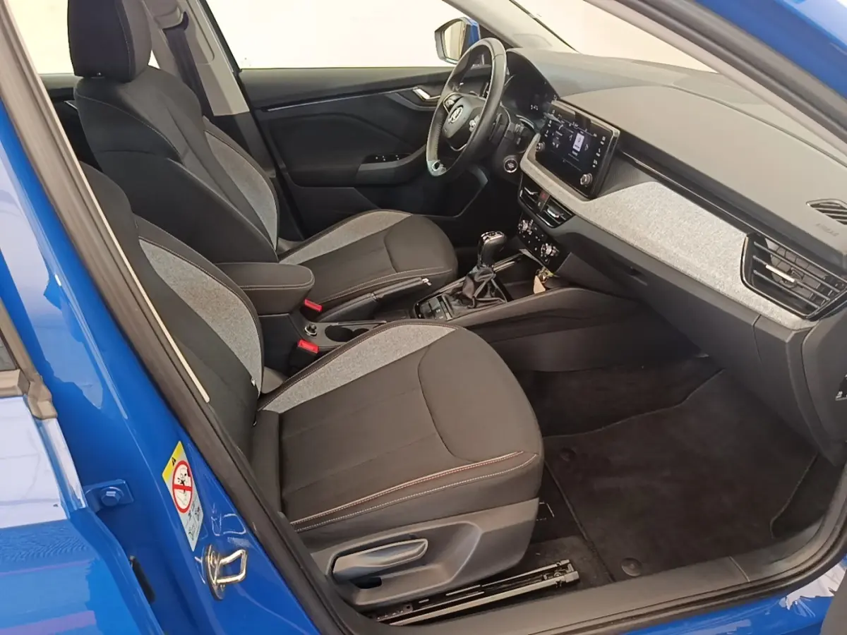 Vue intérieure côté conducteur de la Skoda Scala 1.5 TSI bleu, avec sièges bi-matière et tableau de bord moderne.