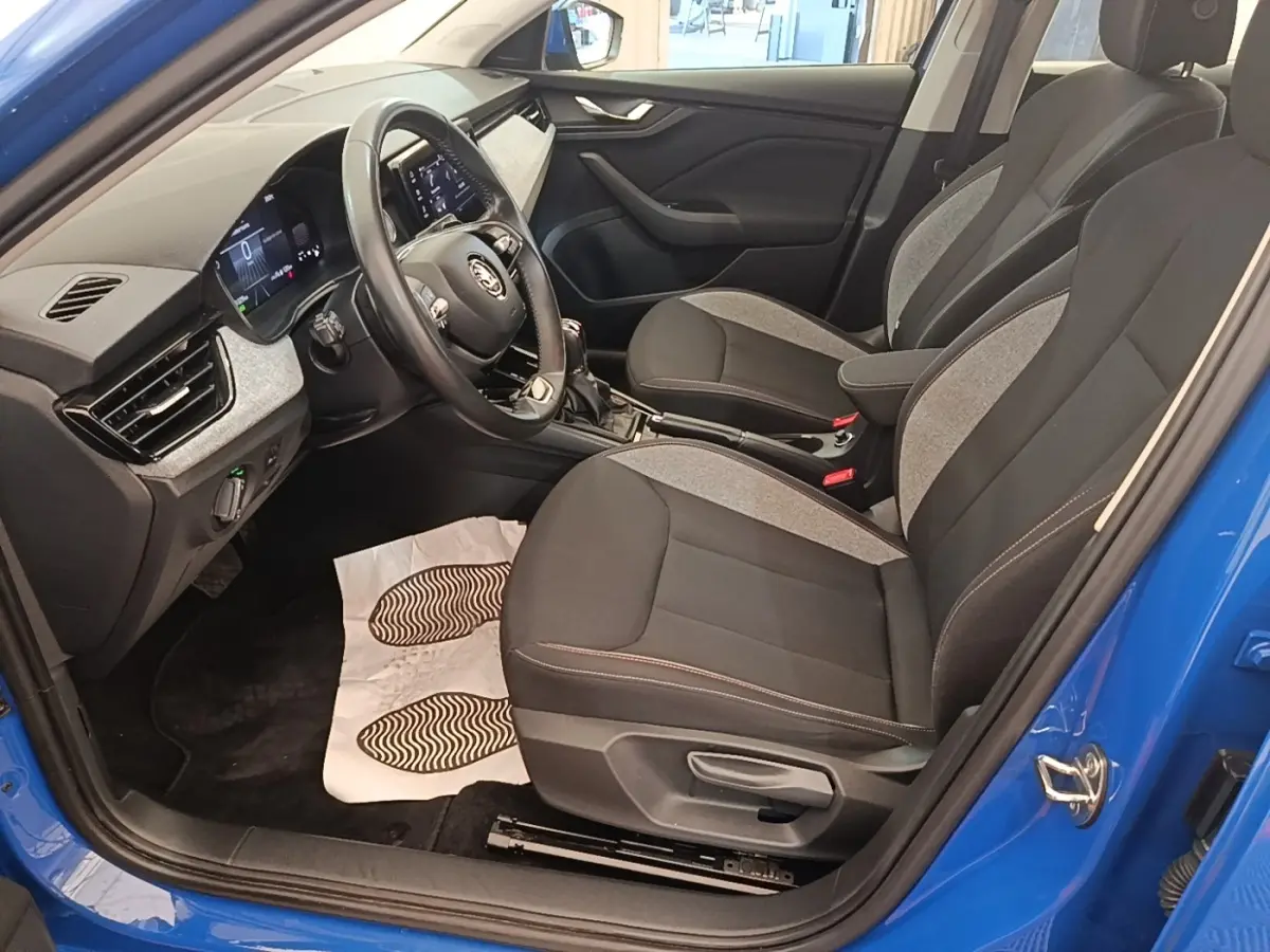 Vue intérieure côté conducteur d'une Skoda Scala 2024 bleu, sièges tissu noir et gris avec volant multifonctions cuir et alu.