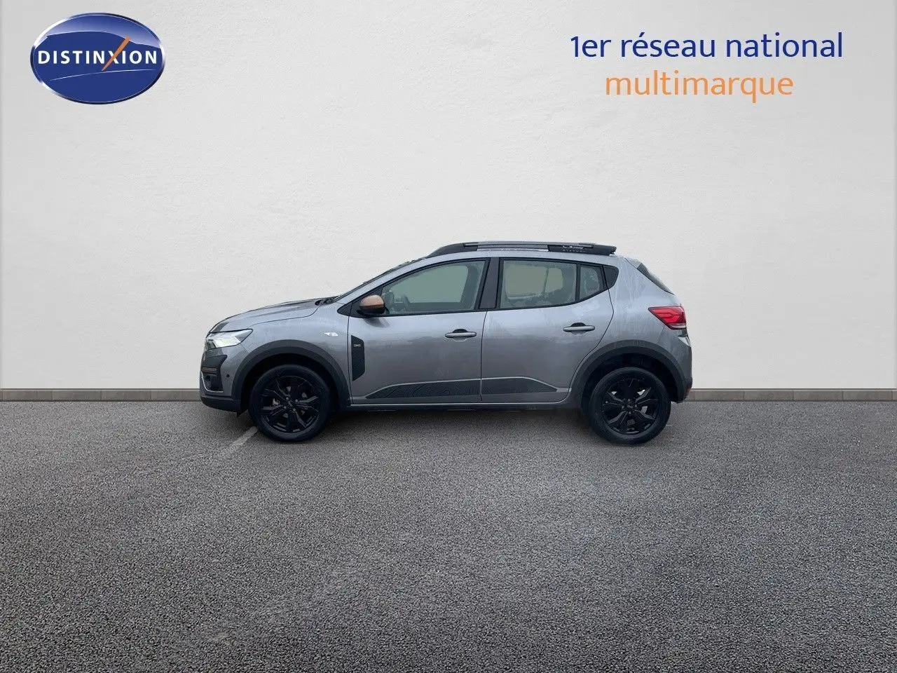 Profil droit d'une Dacia Sandero Stepway 2024 gris schiste métal avec jantes noires et rétroviseurs bronze.