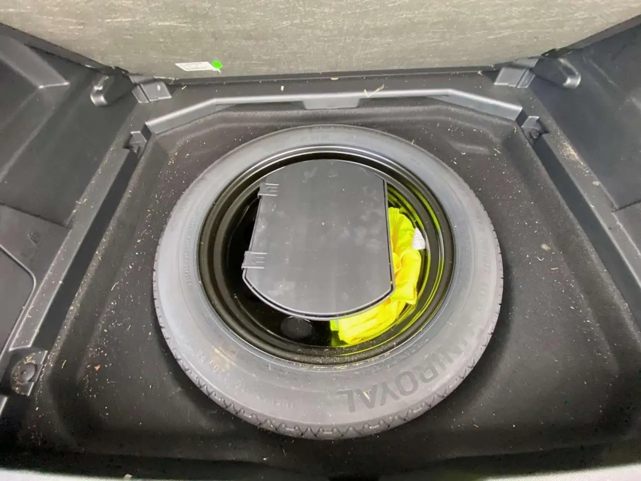 Vue plongeante sur la roue de secours noire et son rangement dans le coffre du Peugeot 3008 noir 2019.