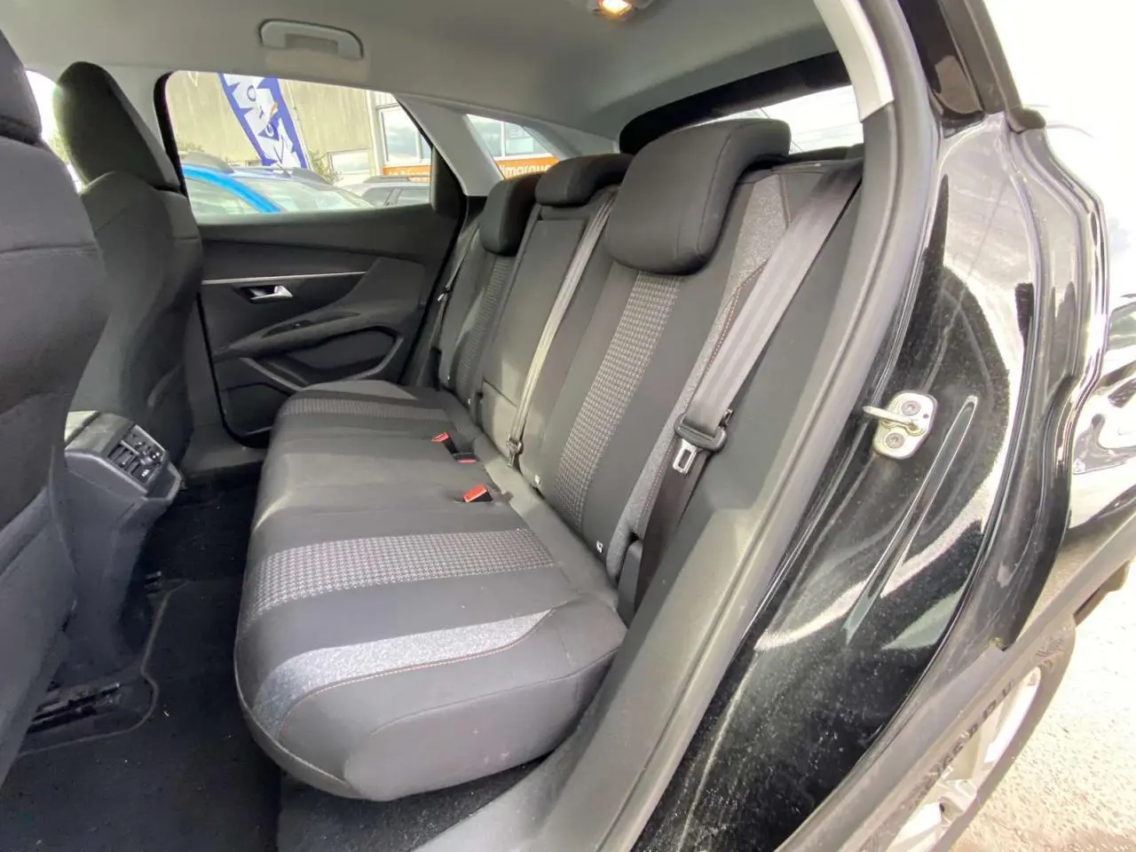 Vue intérieure du siège arrière côté droit d'un Peugeot 3008 noir de 2019 avec sellerie tissu et ceintures grises.