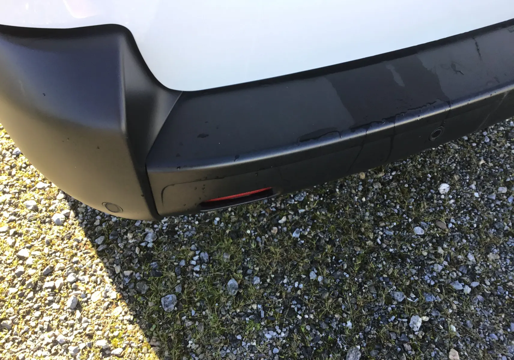 Gros plan sur le pare-chocs arrière noir d'un FIAT Scudo Fourgon blanc, avec capteurs de recul visibles.