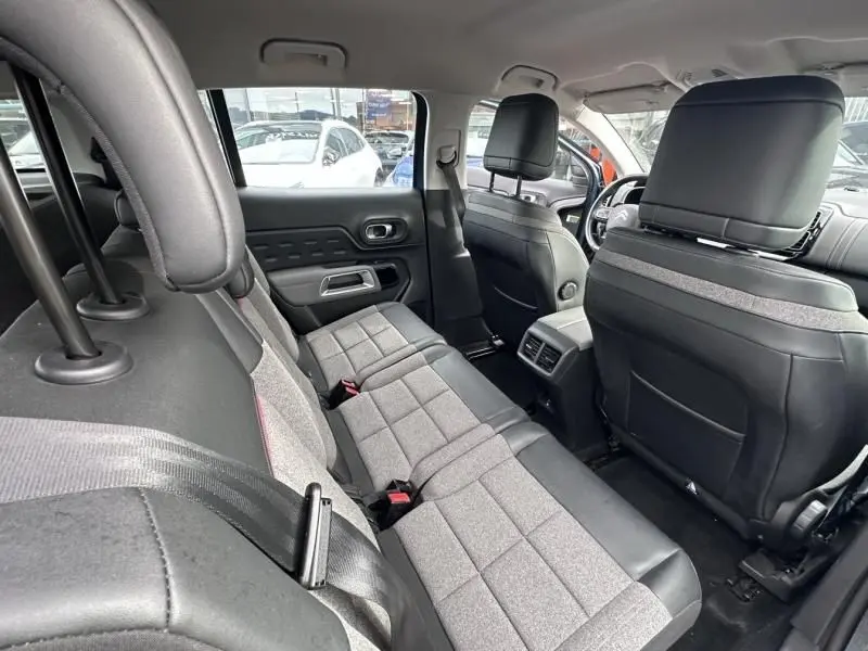 Vue intérieure arrière du Citroën C5 Aircross 2021, sièges tissu gris et cuir noir, avec appuie-têtes et ceintures visibles.