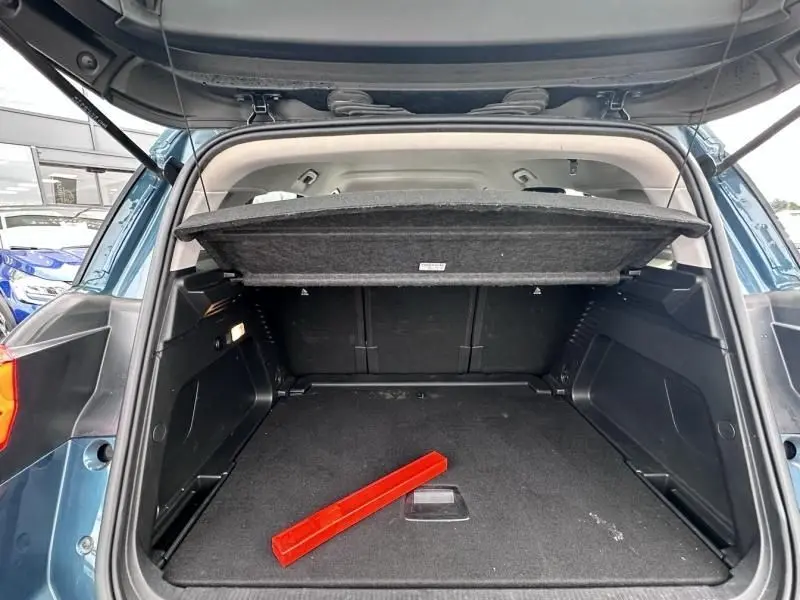 Coffre ouvert vu de l'arrière d'un Citroën C5 Aircross Bleu Tijuca 2021 avec cache-bagages et triangle de signalisation rouge.