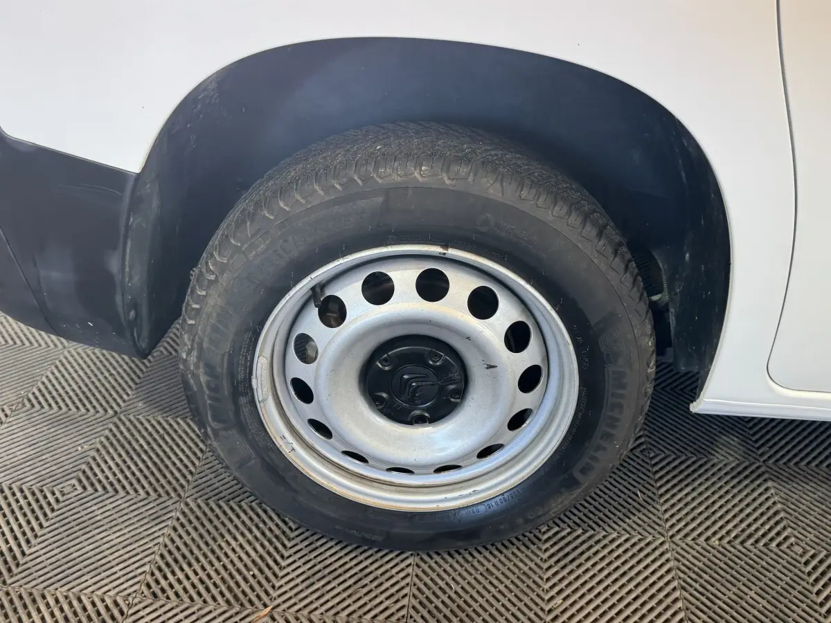 Gros plan sur la roue arrière droite en jante acier du Citroën Berlingo blanc, avec partie basse de la carrosserie visible.