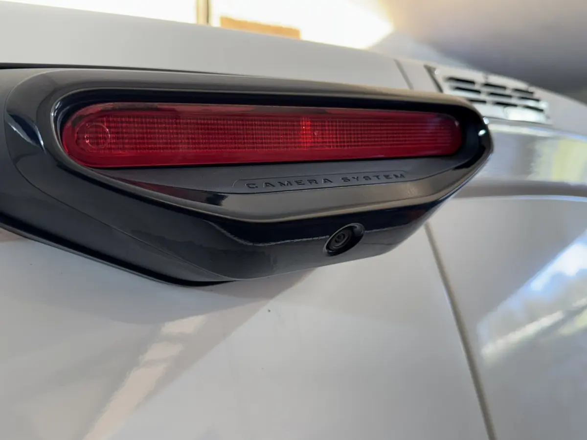 Gros plan sur la caméra de recul intégrée sous le troisième feu stop rouge du Citroën Berlingo blanc.