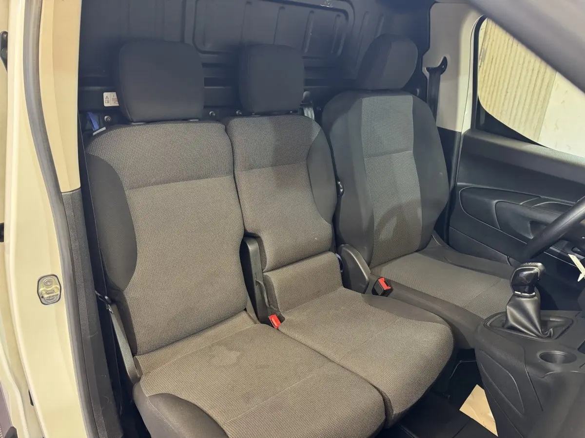 Vue intérieure côté conducteur du Citroën Berlingo blanc 2020 montrant les sièges avant gris et la boîte manuelle.