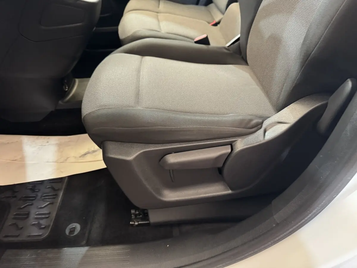 Gros plan sur le siège avant droit gris du Citroën Berlingo blanc, montrant le réglage manuel de l'assise.