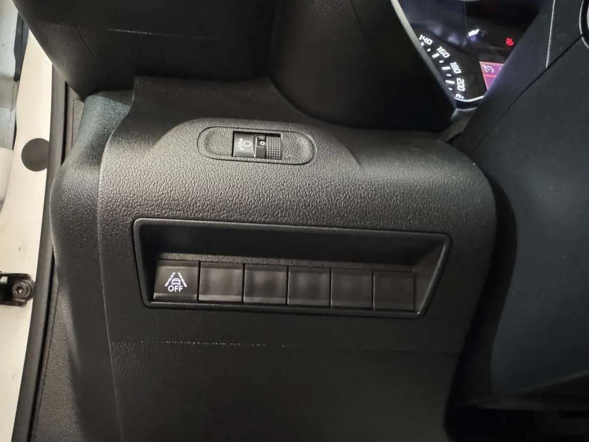 Vue rapprochée du tableau de bord côté conducteur du Citroën Berlingo blanc, avec commande d'éclairage et bouton d'assistance désactivée.