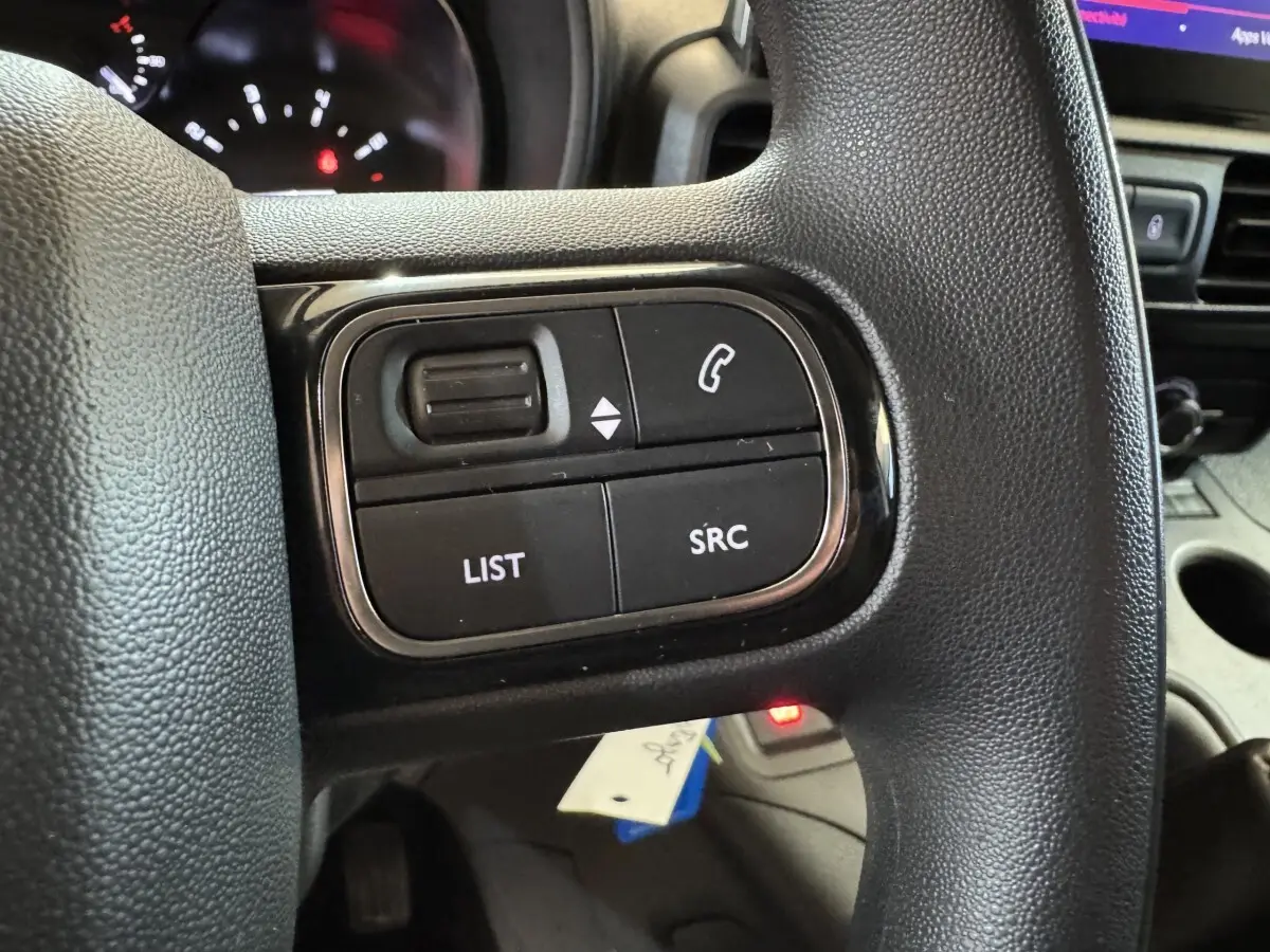 Gros plan sur les commandes multifonctions noires du volant du Citroën Berlingo 2020, intérieur gris.