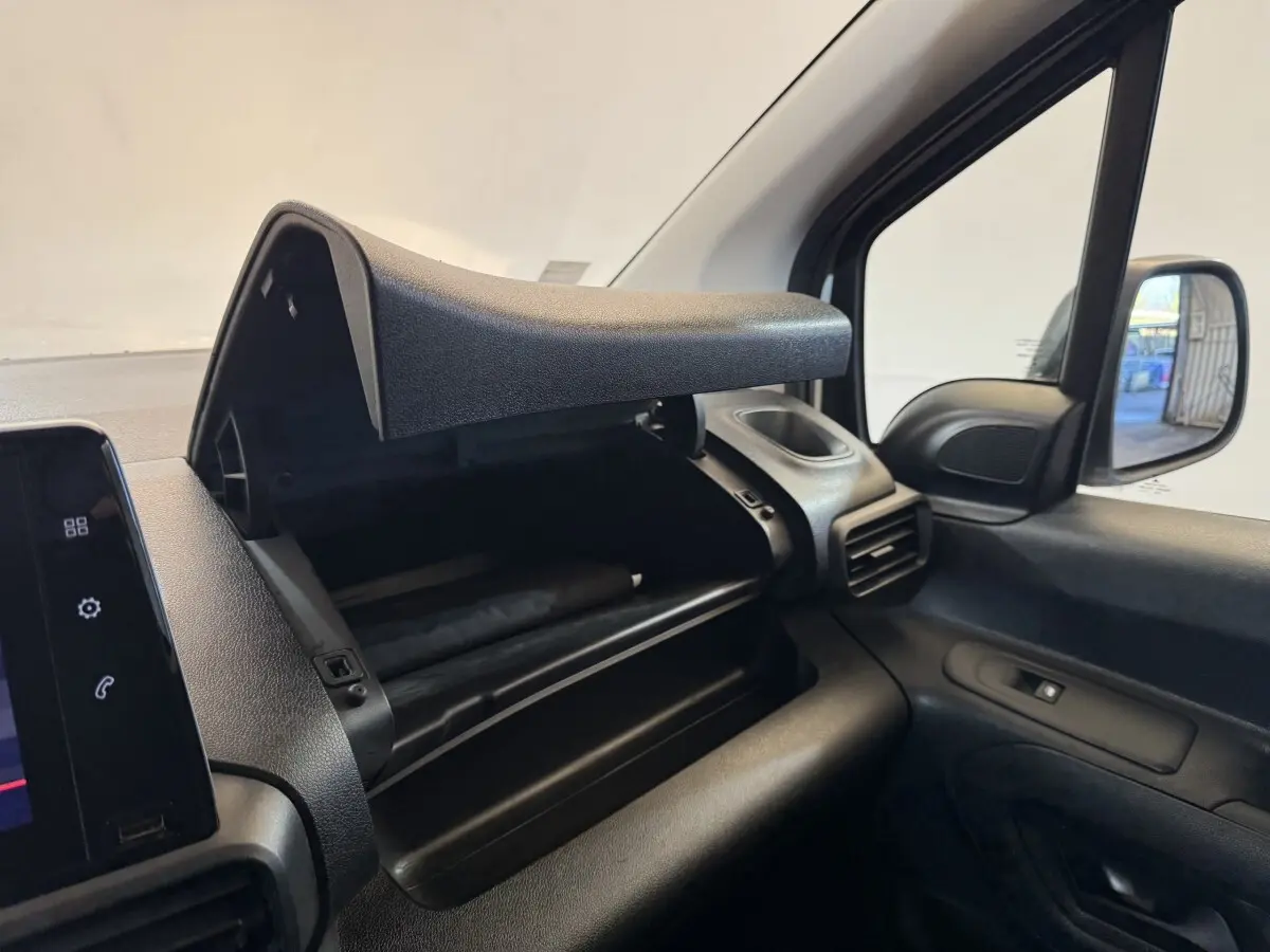 Vue intérieure côté passager du coffre à gants ouvert du Citroën Berlingo blanc, montrant le tableau de bord et la portière.