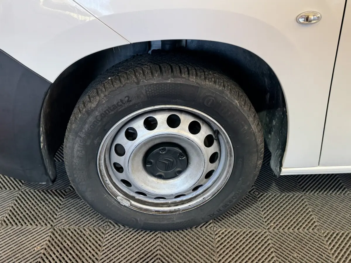 Gros plan sur la roue avant gauche d’un Citroën Berlingo blanc avec jante acier et logo Citroën au centre.
