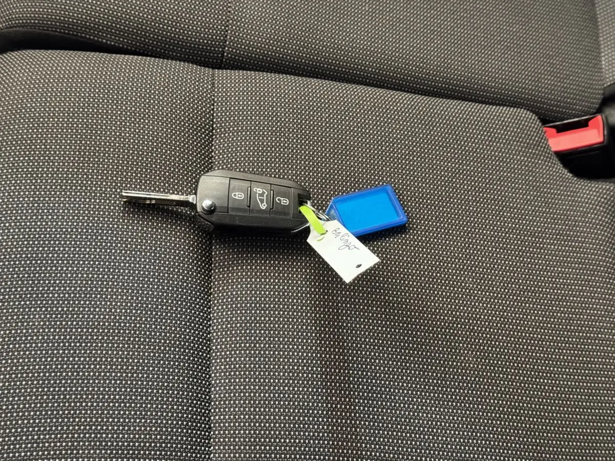 Clé de voiture noire posée sur un siège tissu gris foncé à motifs blancs, intérieur d'un Citroën Berlingo 2020.