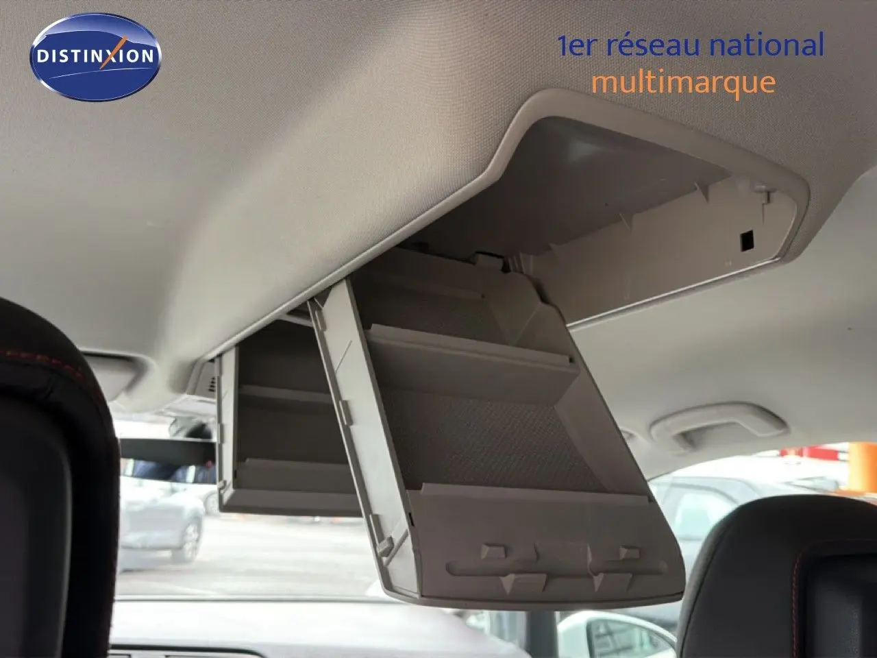 Vue intérieure du coffre à lunettes déplié au plafond d'un Volkswagen Touran blanc de 2018, avec sièges noirs visibles.