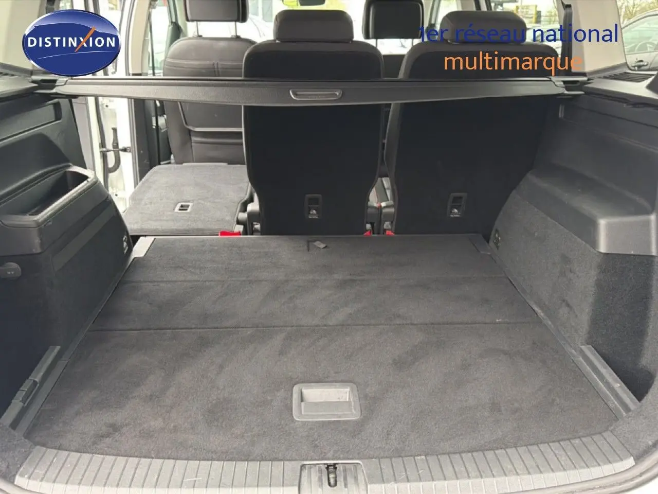 Vue arrière du coffre spacieux du Volkswagen Touran blanc 2018 avec banquette arrière partiellement rabattue.