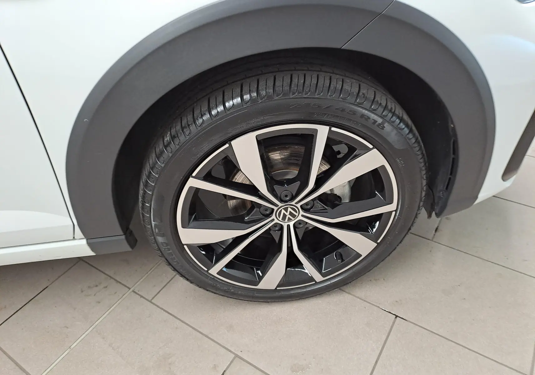 Gros plan sur la jante alliage 18 pouces « Misano » noire et argent du côté avant droit d’un Volkswagen Taigo blanc toit noir.