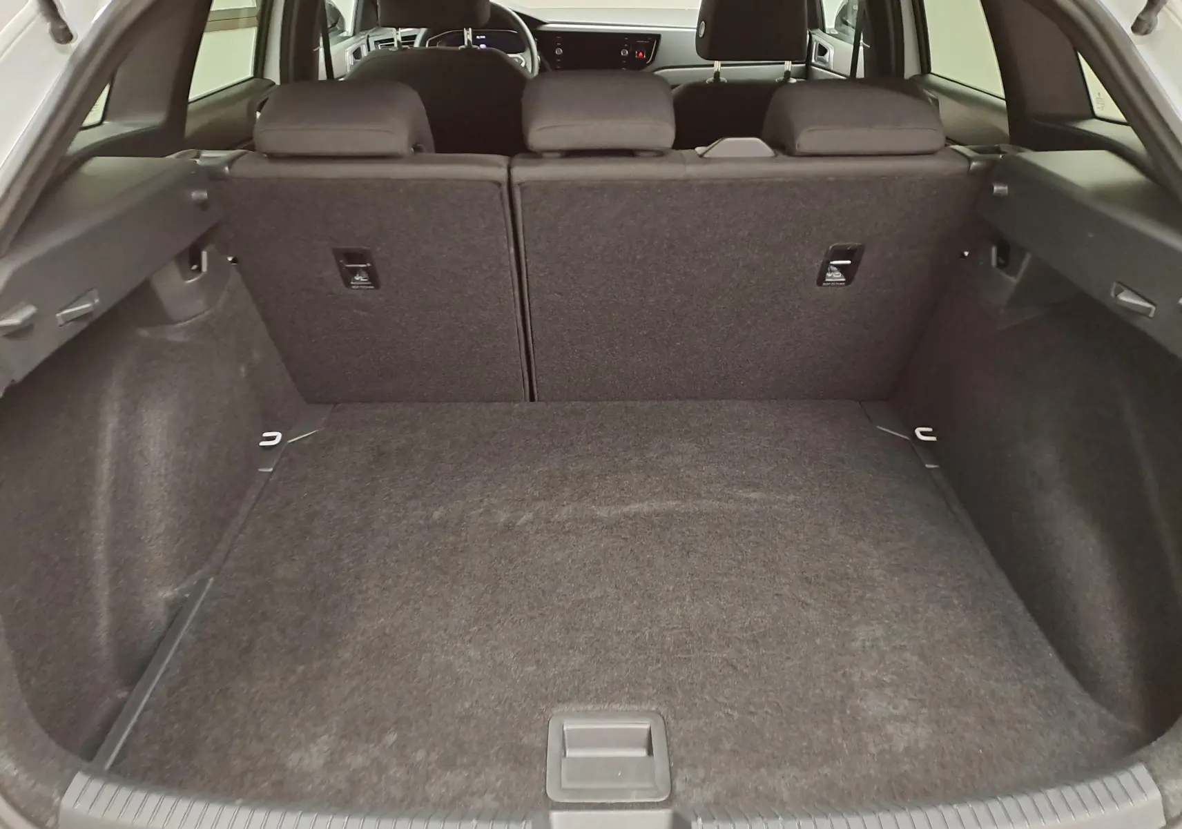 Vue intérieure du coffre spacieux du Volkswagen Taigo 2025, avec sièges arrière rabattables et finition noire.