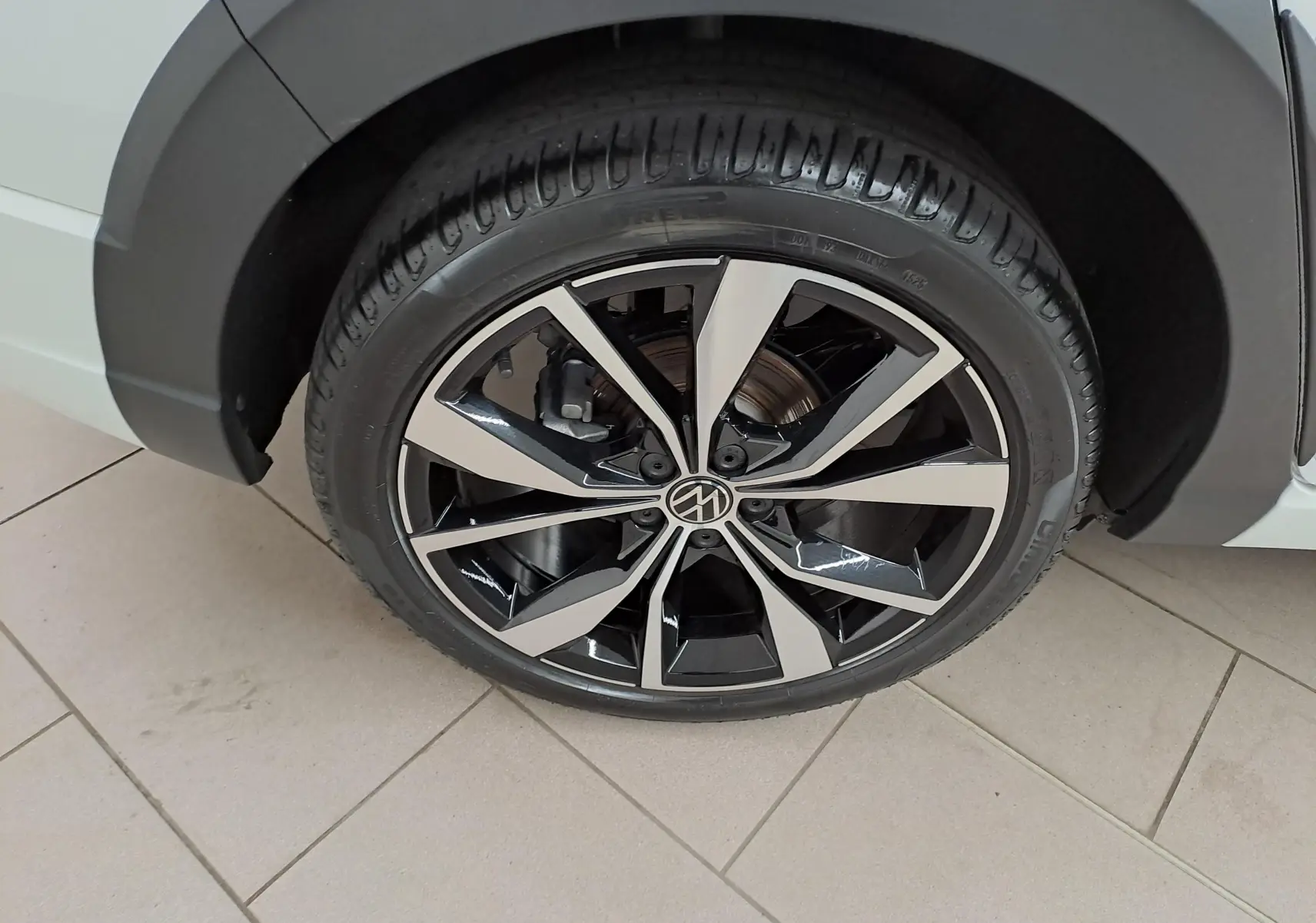 Gros plan sur la jante alliage 18 pouces "Misano" bicolore noir et argent du Volkswagen Taigo blanc toit noir.