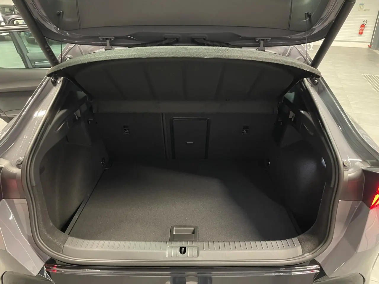 Coffre ouvert vu de l'arrière d'une CUPRA Formentor gris Graphene, intérieur spacieux et tapis noir.