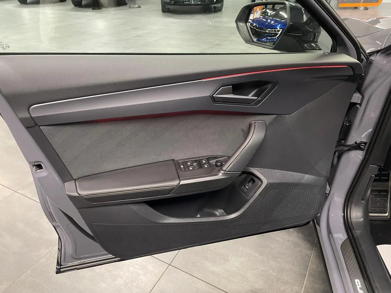 Contre-porte côté conducteur gris Graphene avec surpiqûres cuivrées et bandeau lumineux rouge du CUPRA Formentor 2026.