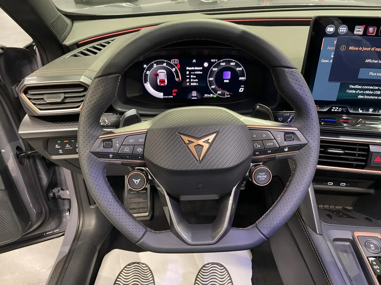 Vue intérieure centrée sur le volant perforé noir avec logo Cupra cuivré et tableau de bord digital du Formentor gris Graphene.