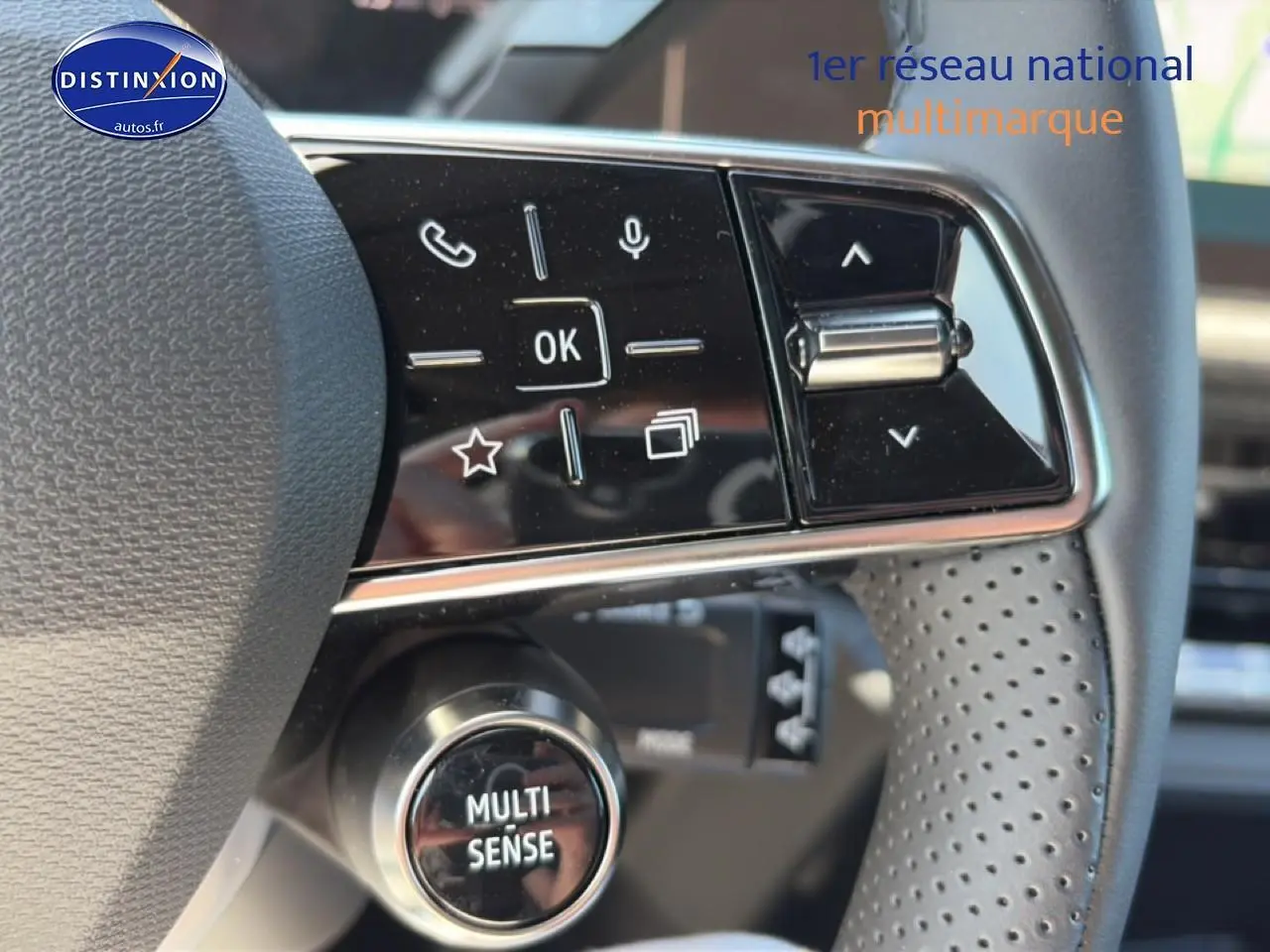 Gros plan sur le volant noir perforé de la Renault Clio VI avec commandes intégrées et bouton Multi-Sense visible.