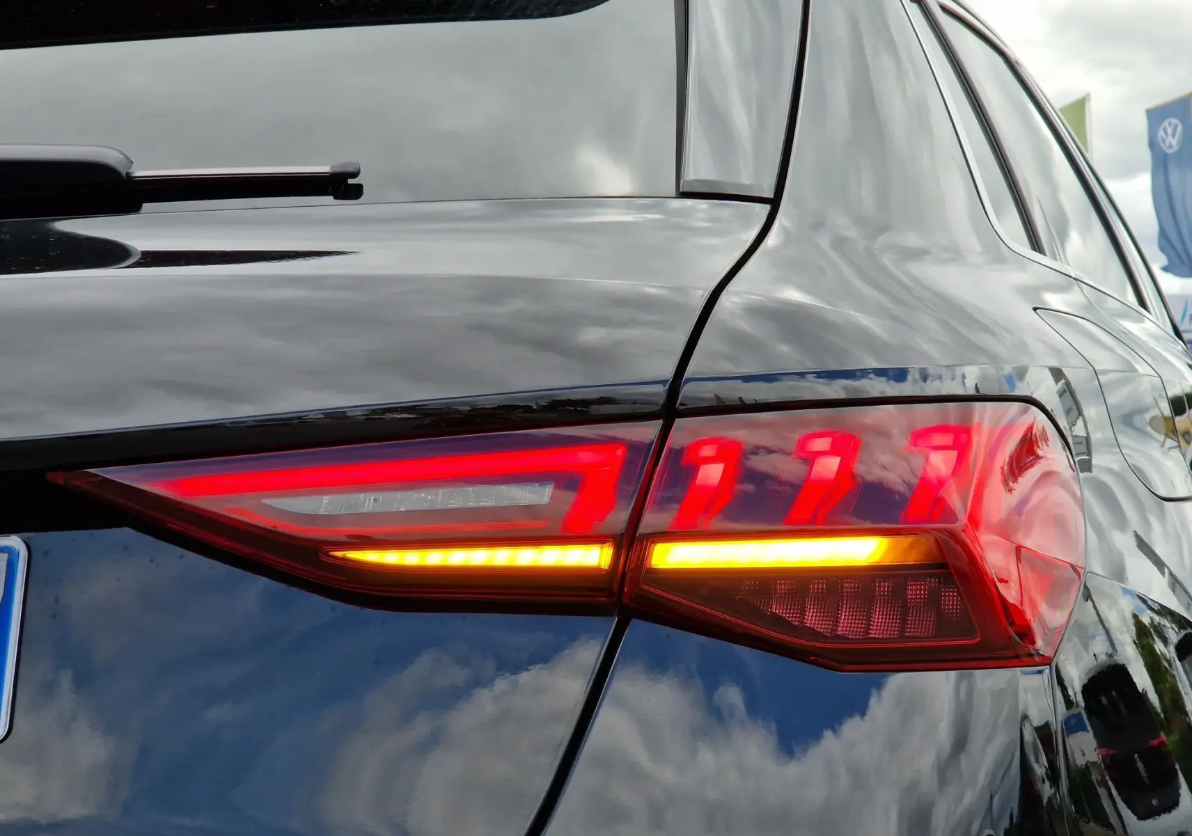 Gros plan sur le feu arrière droit allumé d'une Audi A3 Sportback noire, soulignant ses lignes modernes et lumineuses.