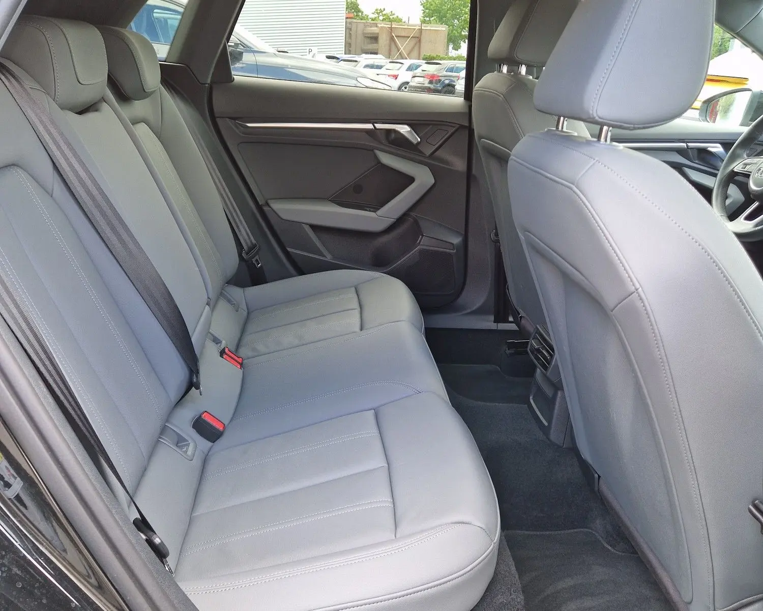 Vue intérieure côté gauche montrant les sièges arrière en cuir gris clair de l'Audi A3 Sportback noire.