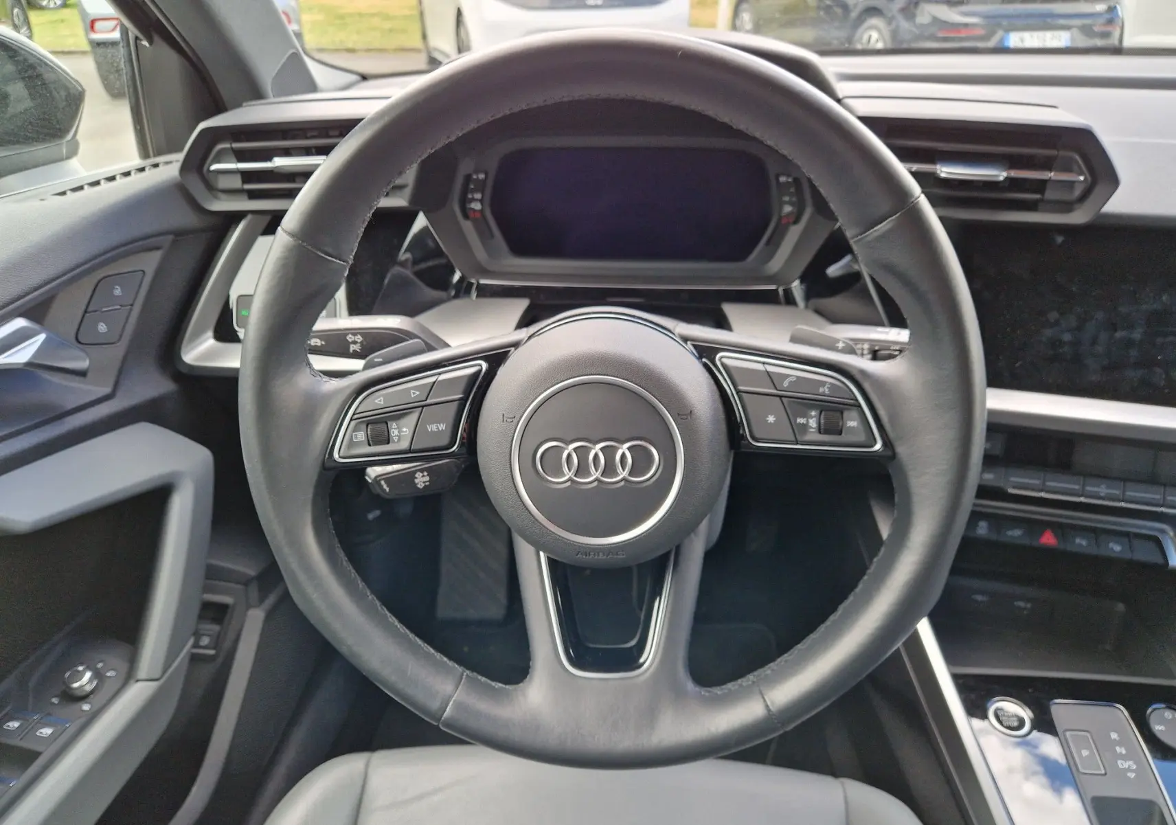 Vue rapprochée du volant en cuir noir de l'Audi A3 Sportback 40 TFSI-e 2021 avec commandes intégrées et tableau de bord digital.