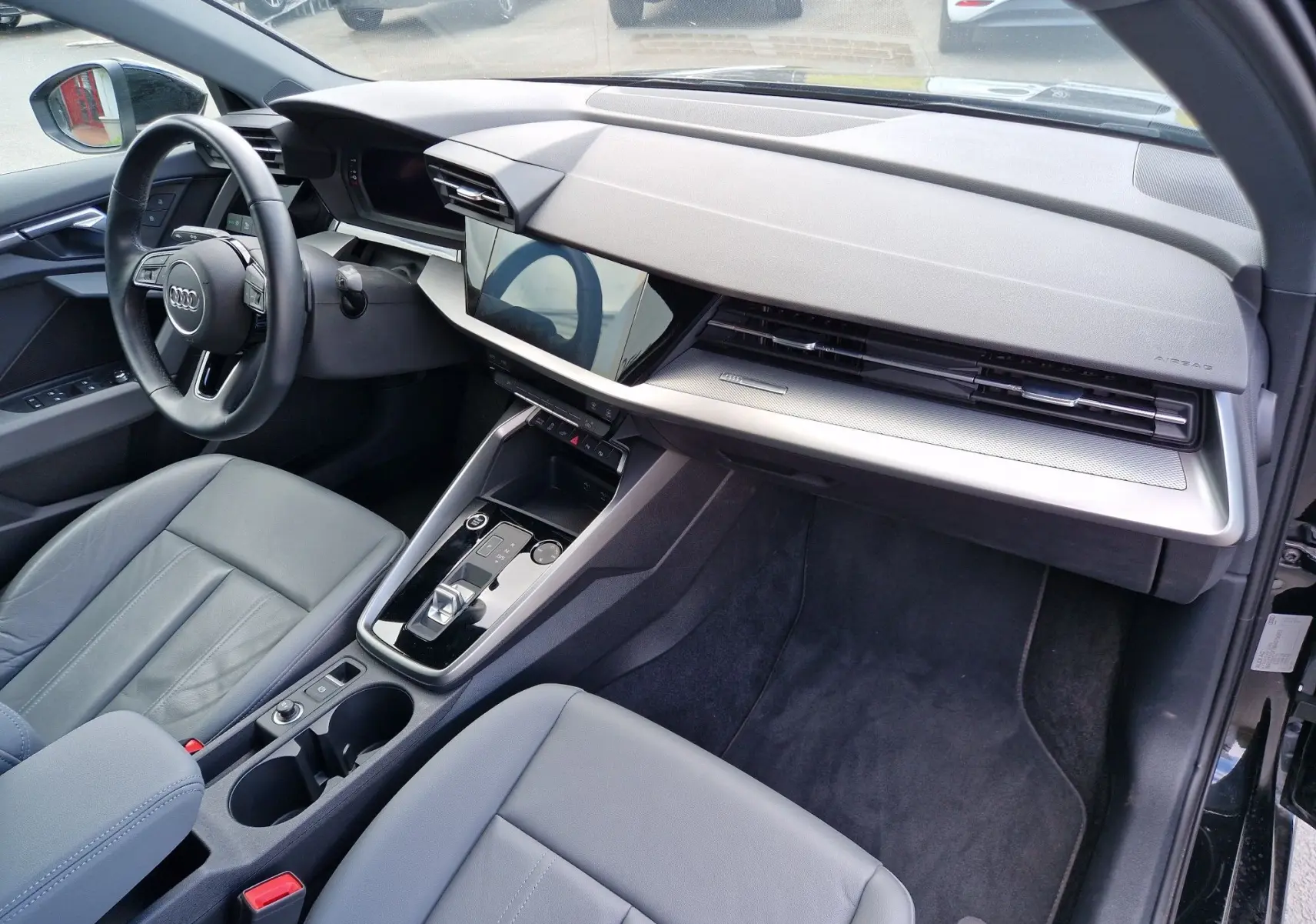 Vue intérieure côté conducteur de l'Audi A3 Sportback 40 TFSI-e 2021, avec tableau de bord moderne et sièges cuir gris.