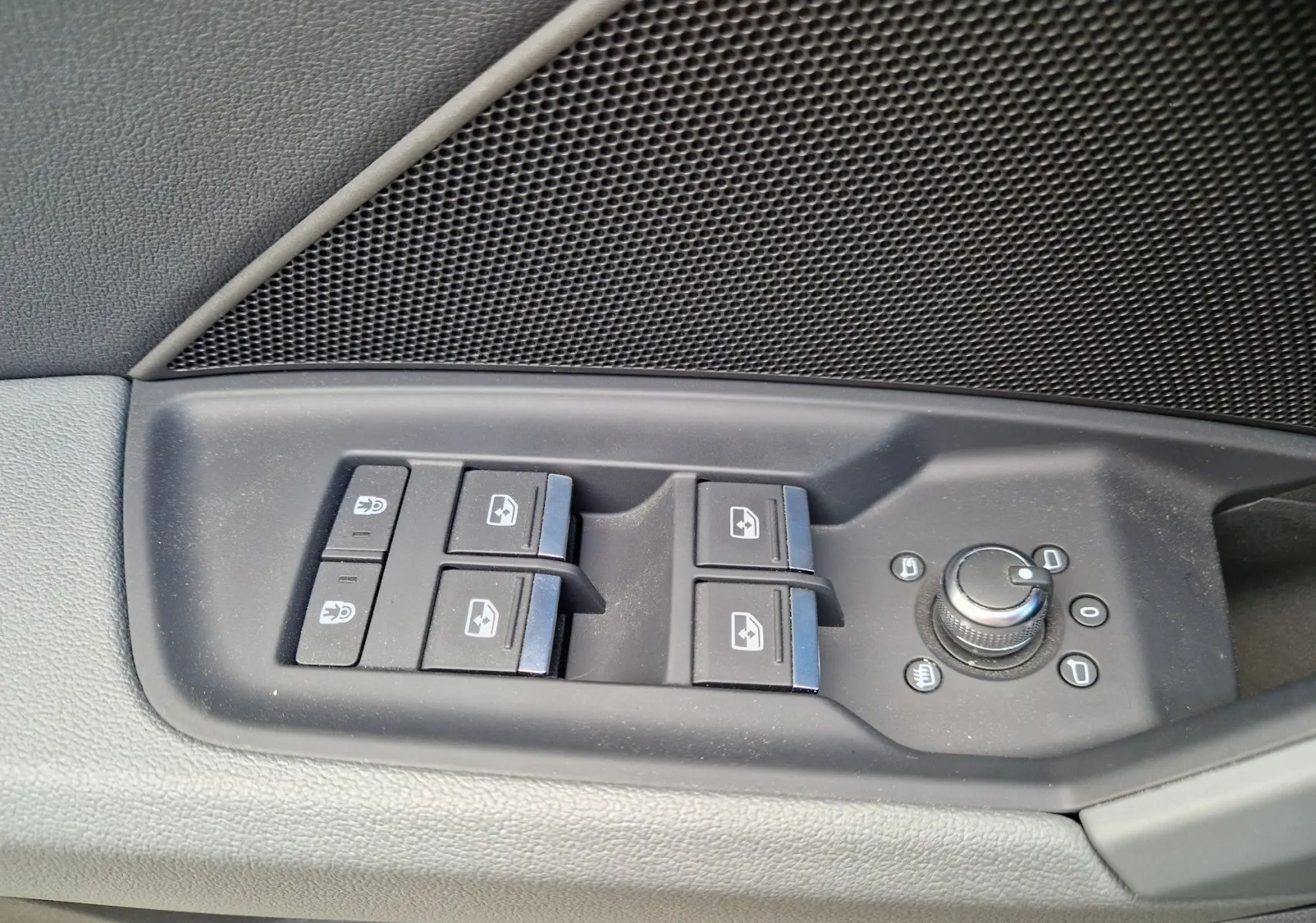 Gros plan sur les commandes de lève-vitres et réglage des rétroviseurs côté gauche d’une Audi A3 Sportback noire.