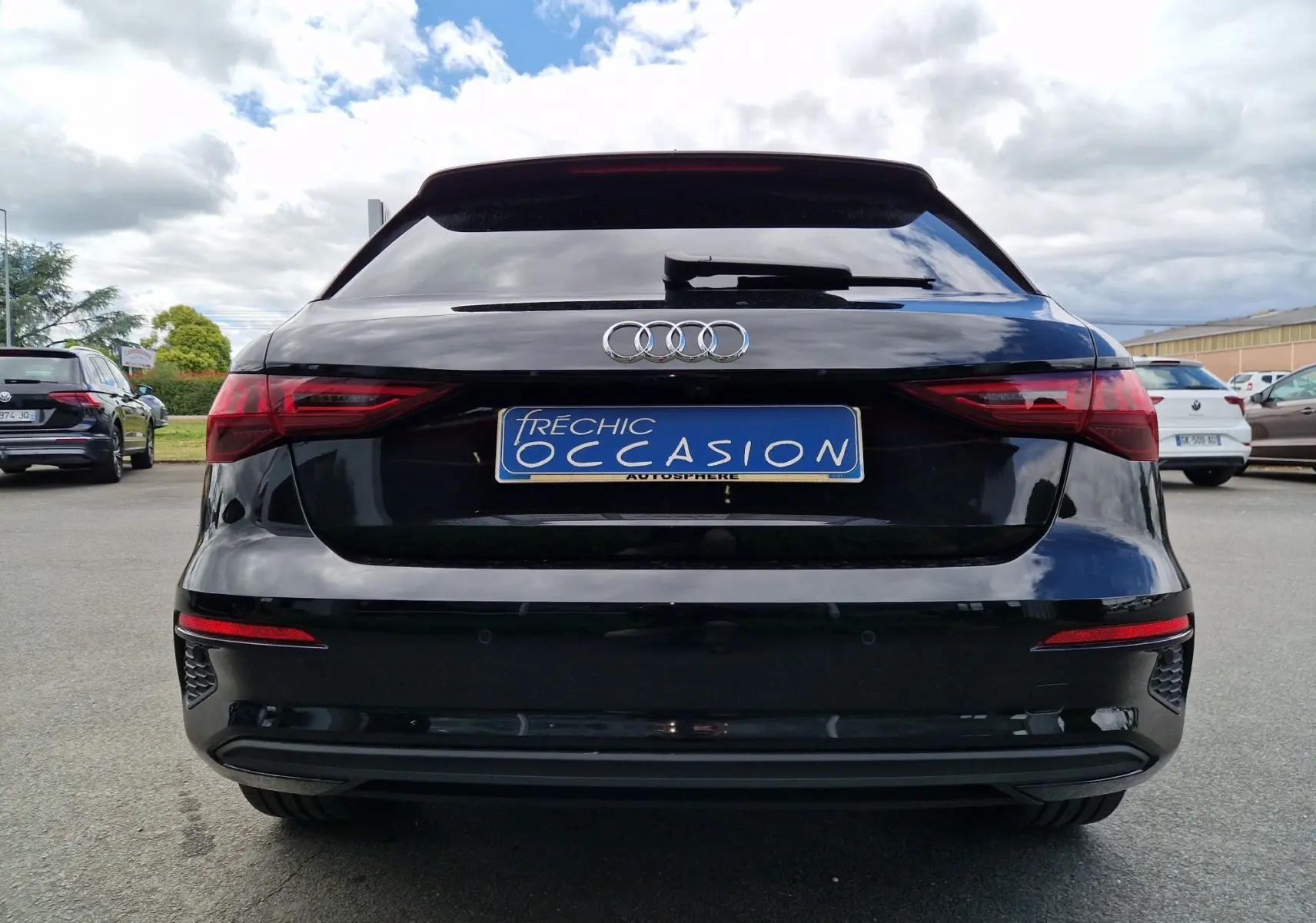 Vue arrière d'une Audi A3 Sportback noire 2021 avec feux LED et logo Audi bien visibles sur un parking extérieur.
