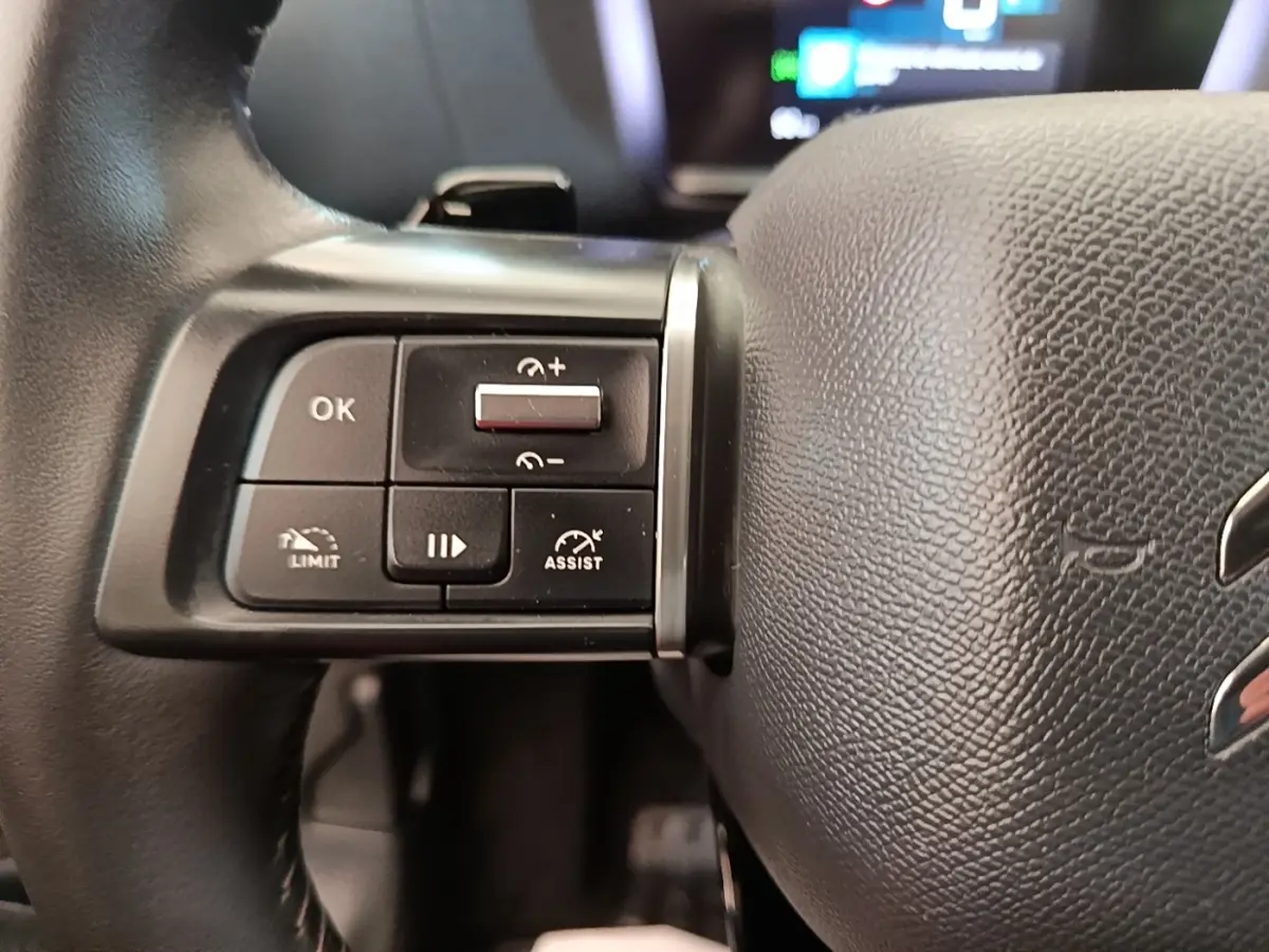 Gros plan sur les commandes multifonctions à gauche du volant cuir noir du Citroën C4 X 2023.