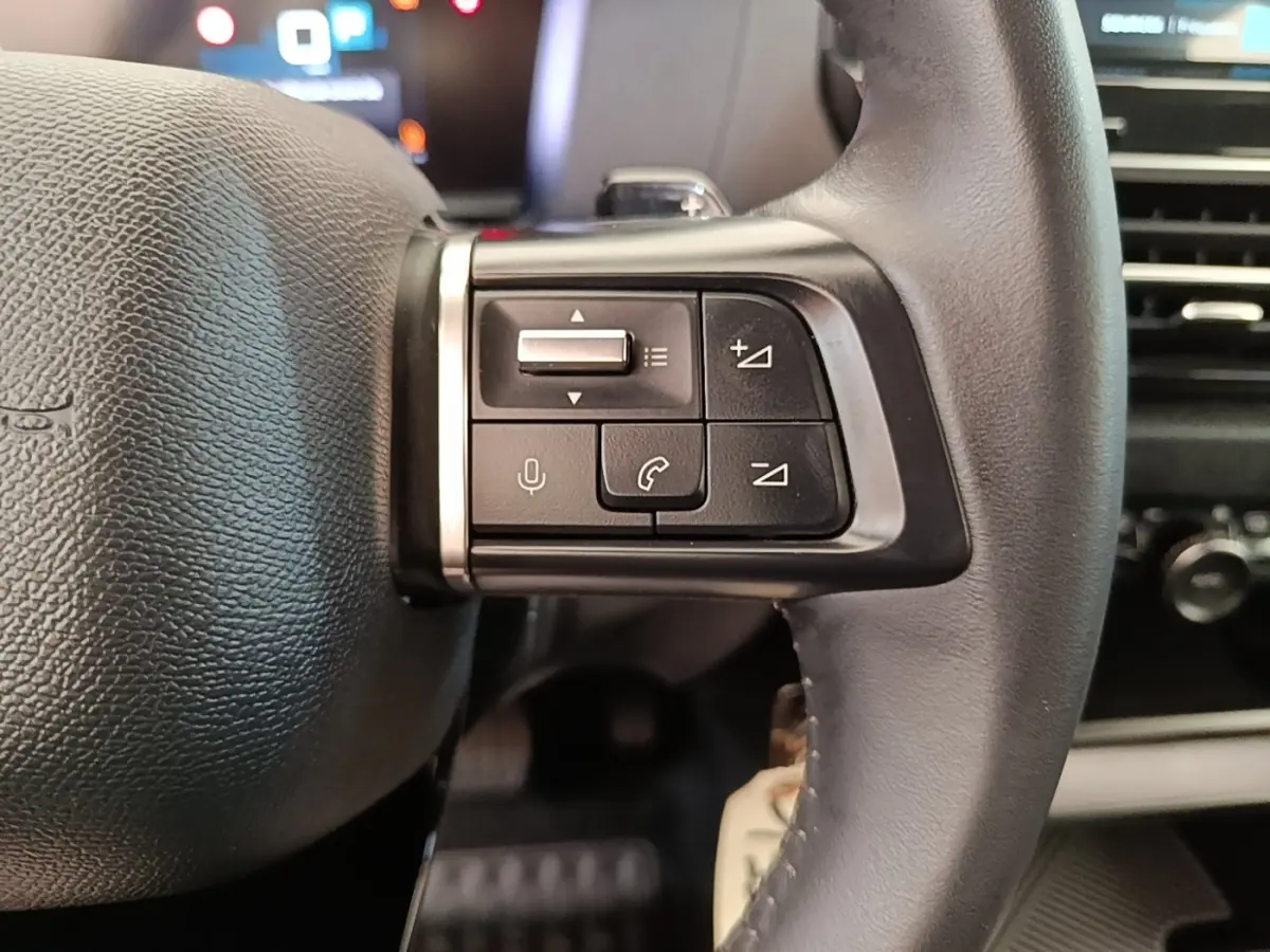 Gros plan sur le côté droit du volant cuir noir de la Citroën C4 X 2023 avec commandes multifonctions.