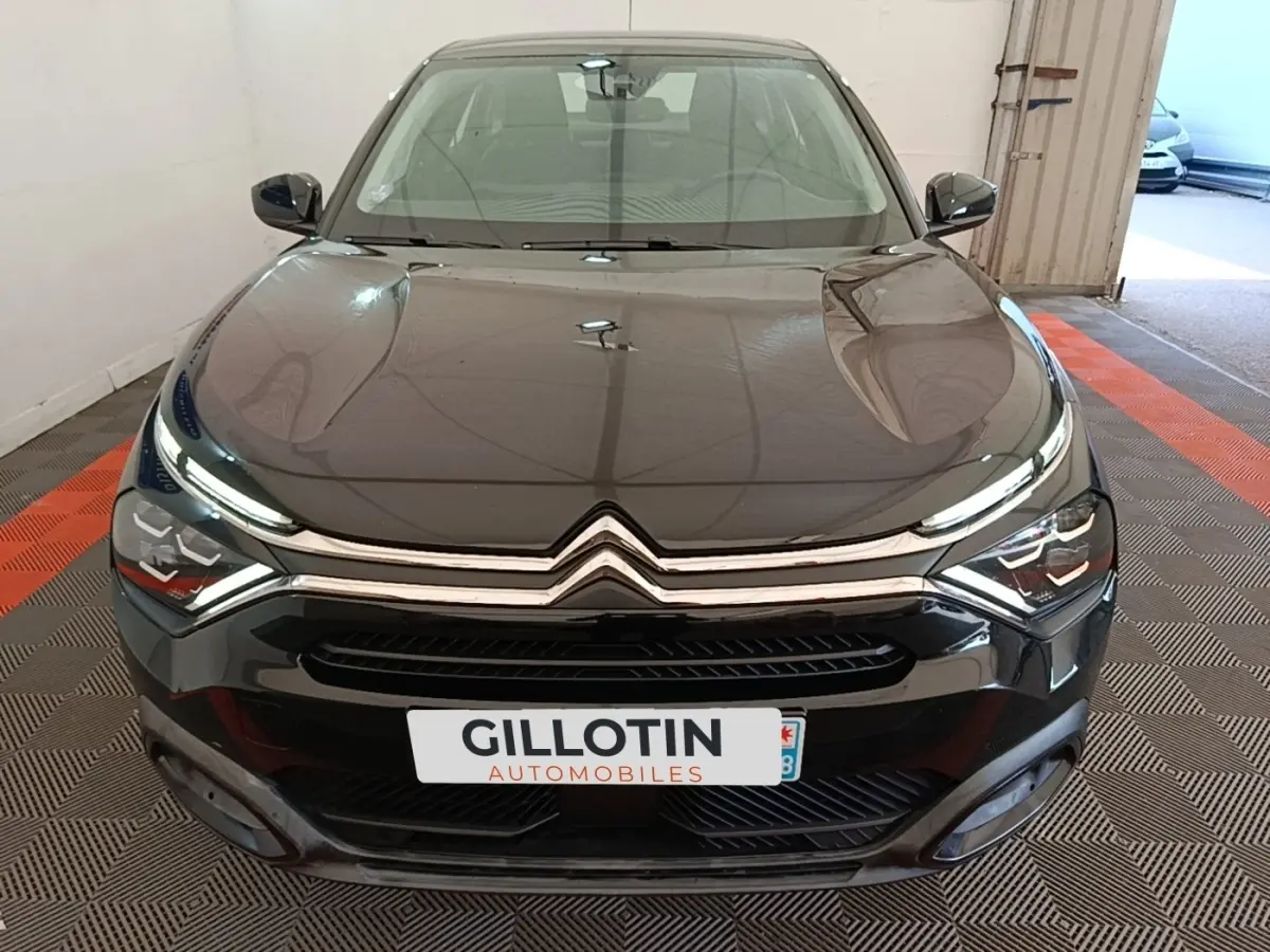Vue avant d'une Citroën C4 X noire 2023 avec calandre chromée et phares LED distinctifs dans un garage.