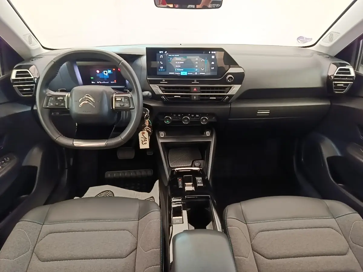 Vue intérieure avant du tableau de bord noir de la Citroën C4 X avec volant cuir multifonctions et écran tactile central.