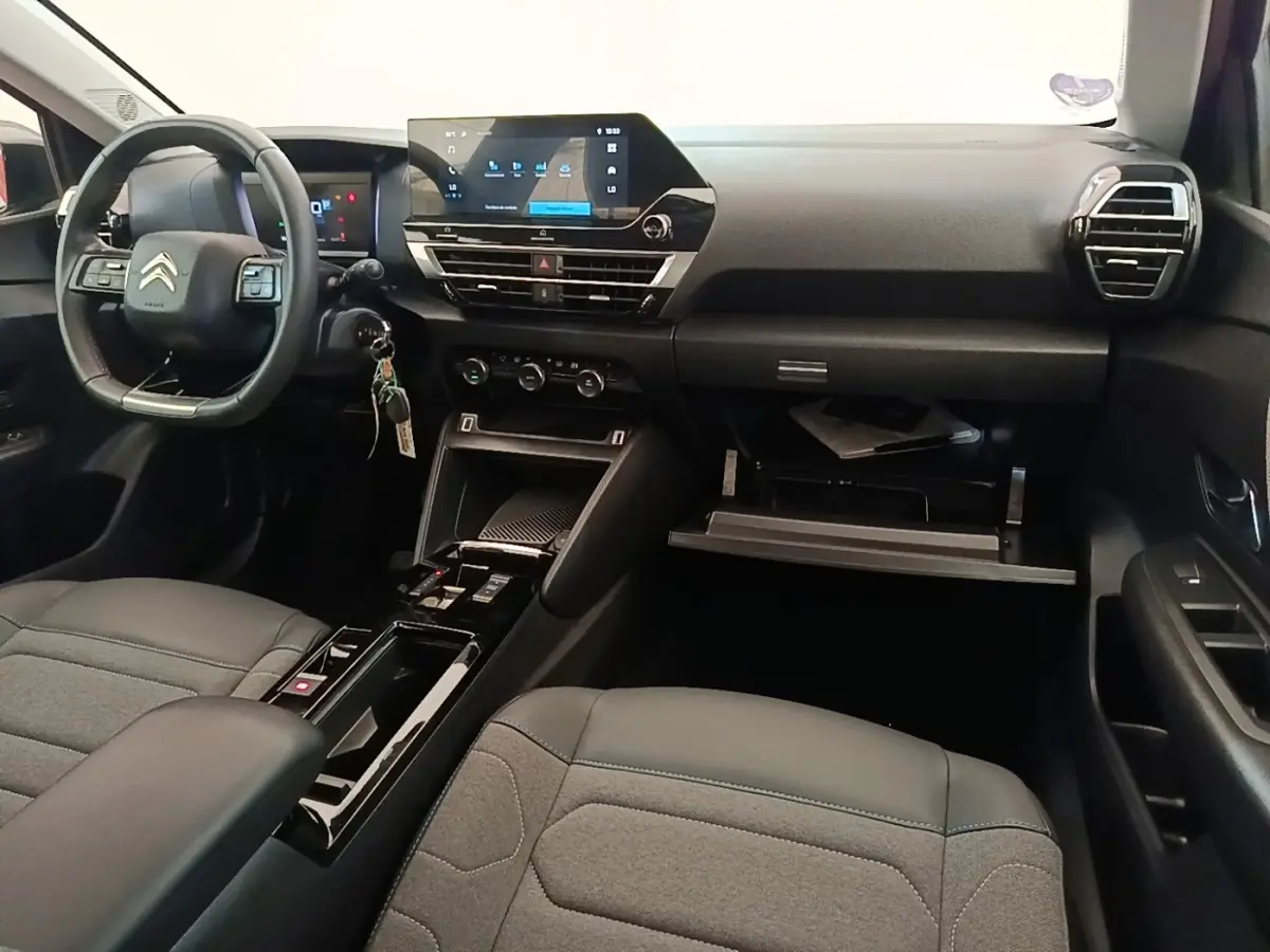 Intérieur noir de la Citroën C4 X 2023, vue du poste de conduite avec volant cuir multifonctions et écran tactile central.