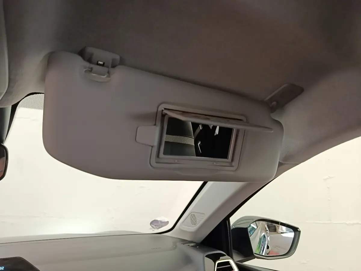 Détail intérieur montrant le pare-soleil côté conducteur avec miroir intégré et rétroviseur extérieur noir.