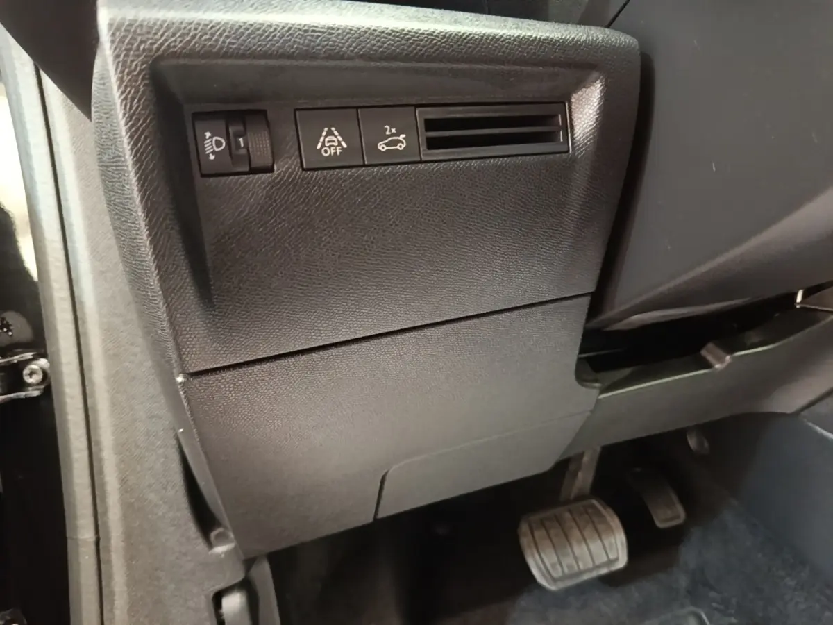 Détail intérieur côté gauche du tableau de bord noir de la Citroën C4 X avec commandes d’éclairage et assistance.