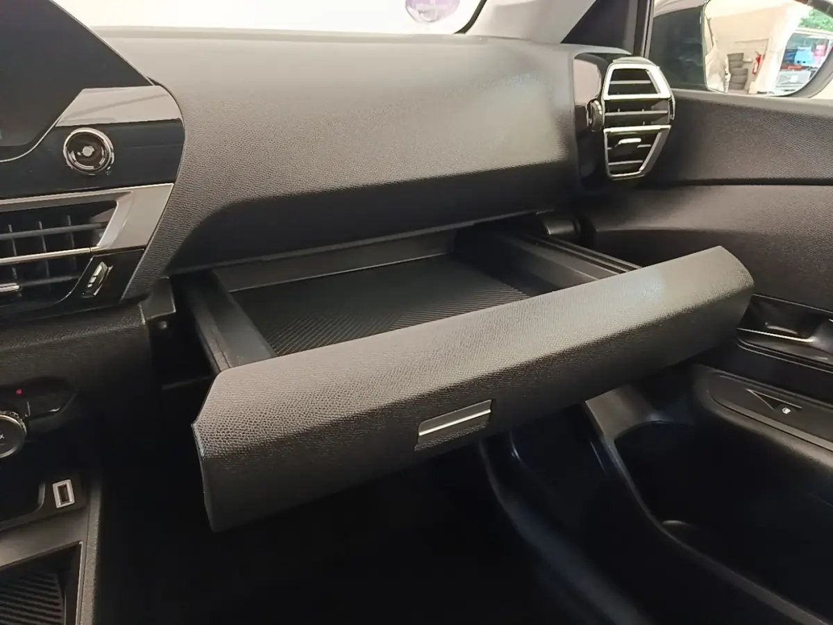 Intérieur de la Citroën C4 X noir, vue du tableau de bord côté passager avec boîte à gants ouverte.