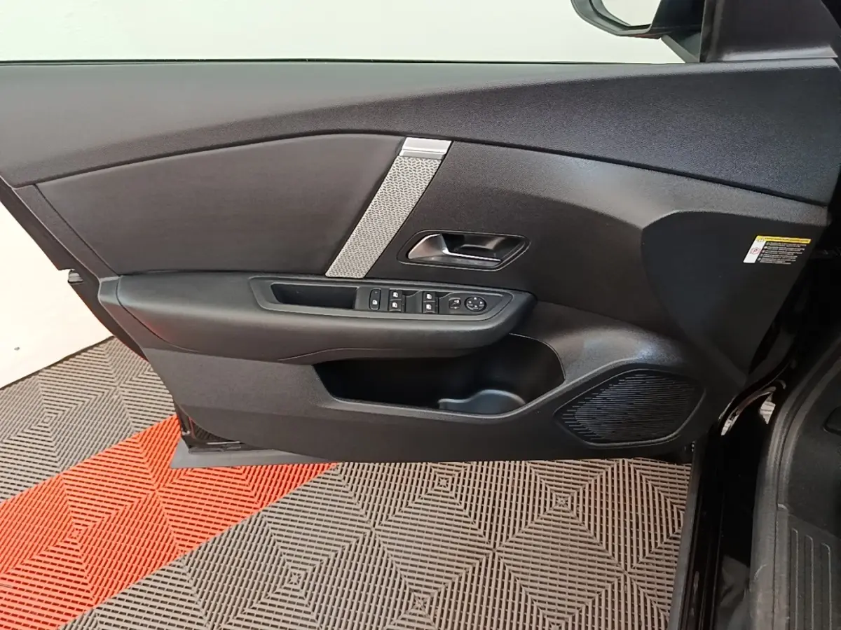 Vue intérieure côté gauche de la porte avant noire de la Citroën C4 X avec commandes de vitres et haut-parleur intégré.