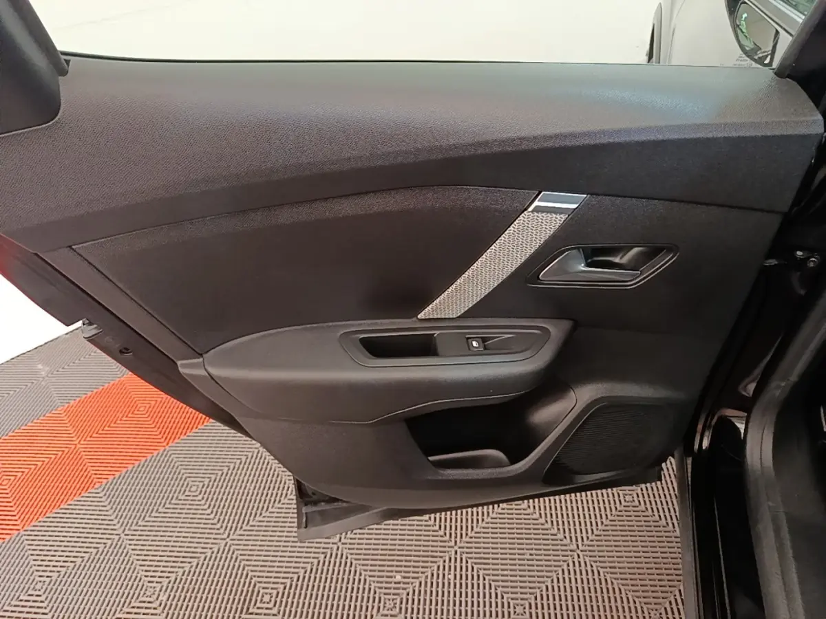 Vue intérieure de la porte avant gauche noire du Citroën C4 X 2023 avec poignée et commande de vitre intégrées.