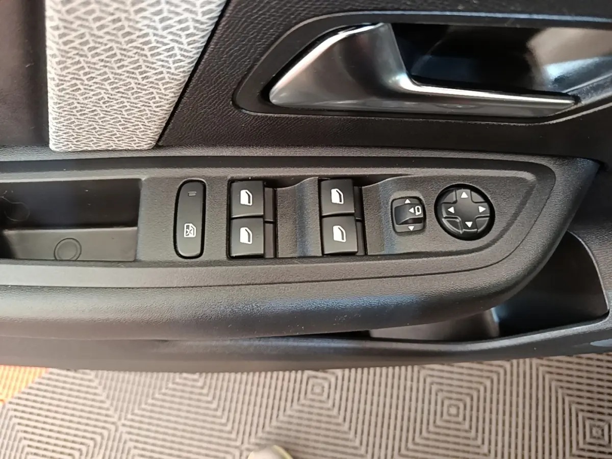 Gros plan sur la commande des vitres et rétroviseurs côté conducteur du Citroën C4 X noir, intérieur tissu et plastique noir.