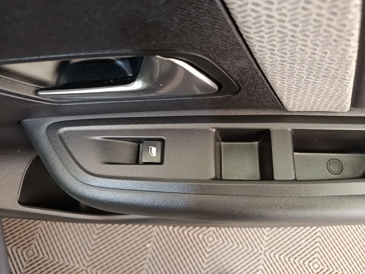 Gros plan sur la poignée intérieure et commande de lève-vitre côté conducteur d'une Citroën C4 X noire.