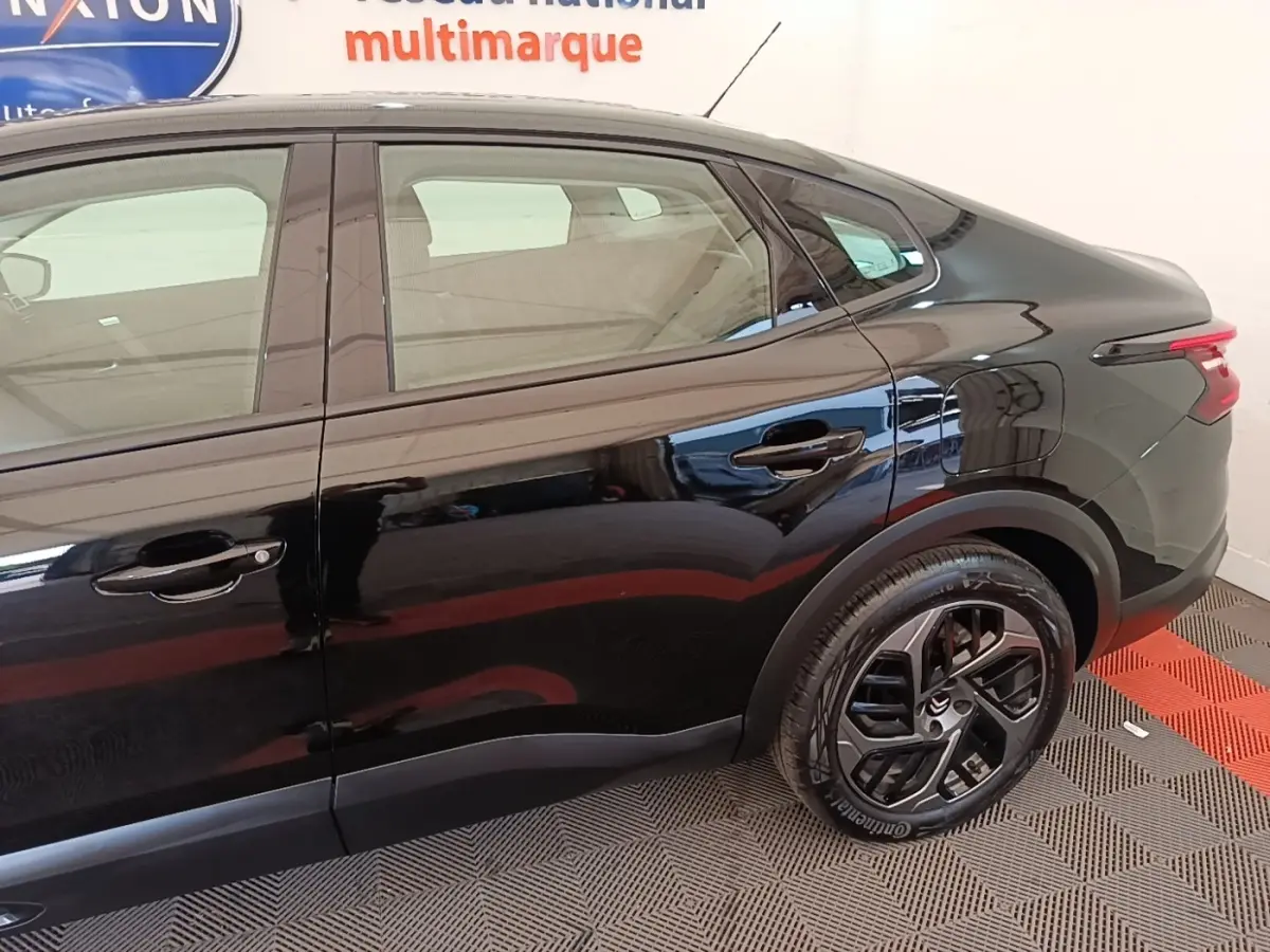 Vue côté droit arrière d'une Citroën C4 X noire 2023 avec jantes noires et feux arrière LED distinctifs.
