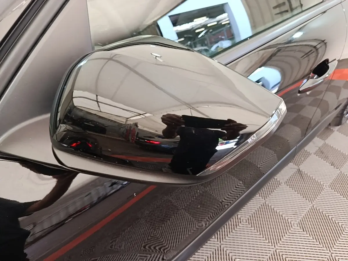 Rétroviseur droit noir brillant de la Citroën C4 X 2023, avec poignée de porte et carrosserie noire en reflet.